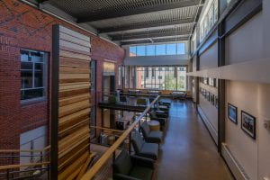 An image of the third floor atrium, it's a wide open space with lots of seating and a wall for displaying student work.