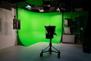 An image of the production studio green screen corner. The wall is painted chroma key green and brightly lit.